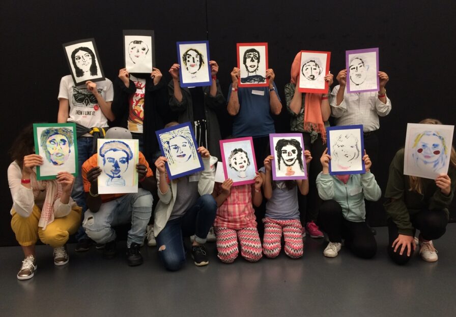 Foto einer Workshopgruppe mit gedruckten und farbig gestalteten Selbstporträts.