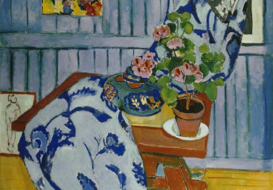 Eine harmonische, zweidimensional wirkende Farbkomposition zeigt ein Stillleben auf einem Tisch mit einem floral gemusterten Stoff, einer ovalen Form und einem Geranientopf.