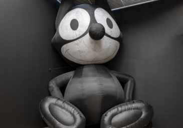 Ausstellungsansicht mit aufgeblasener Plastikkatze in der Ecke