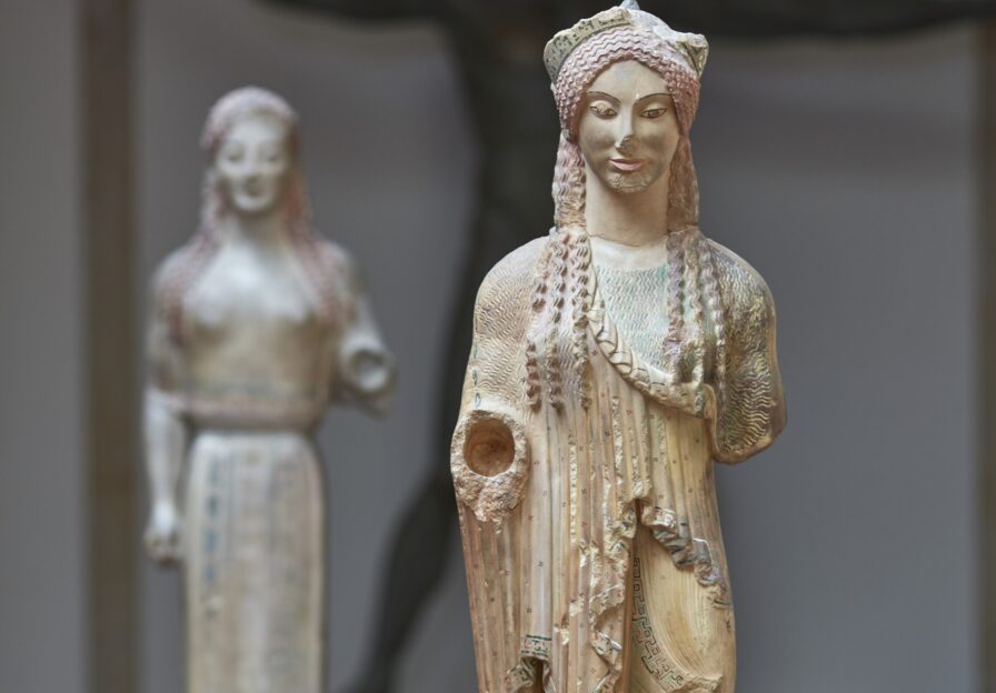 Farbiger Abguss einer griechischen Frauenstatue mit reichem Gewand und Diadem im Haar.