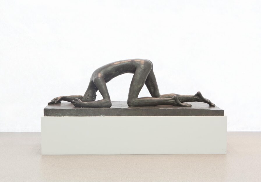 Knieende und vorn über gebeugte, nackte, männliche Bronzefigur mit abgebrochenem Schwert in der Hand.