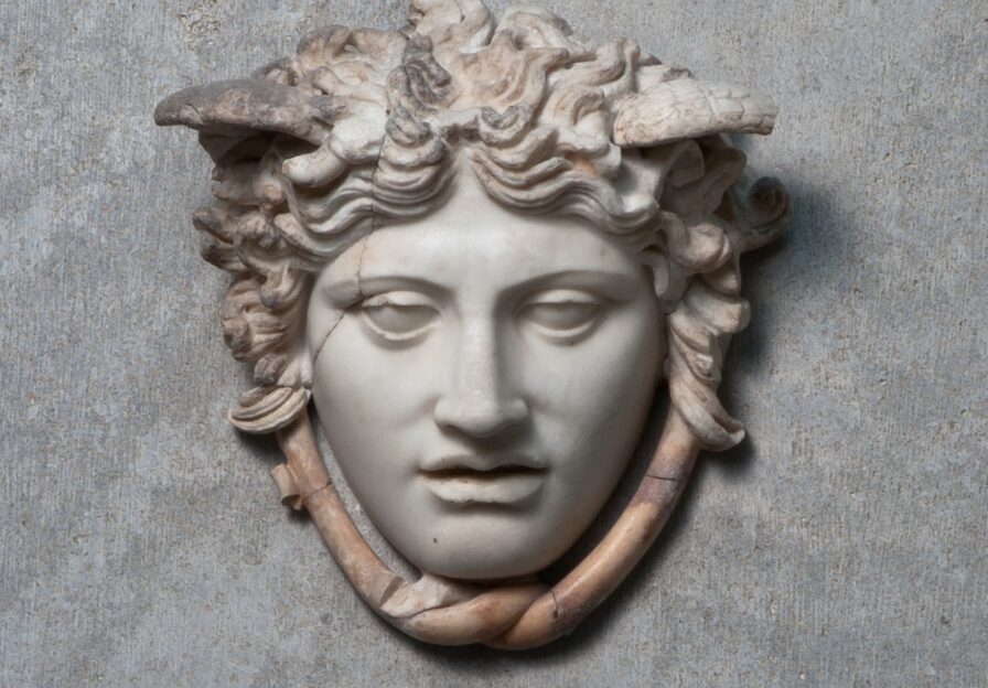 Antiker Reliefkopf der Medusa aus Marmor mit Flügeln und Schlangen um den Hals.
