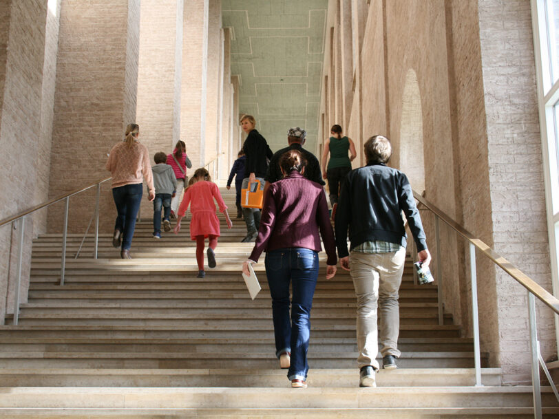 Erwachsene erklimmen die Aufgangstreppe der Alten Pinakothek.