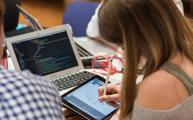 Jugendliche arbeitet mit Laptop und Zeichen-Tablet.