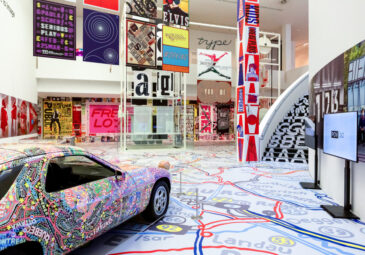 Blick in die Ausstellung: Säulen, Autos, Boden, alles voller buntem Design.