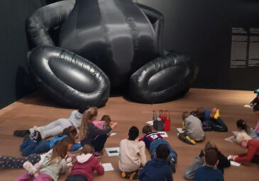 Eine Schulklasse sitzt verstreut am Boden vor einem riesigen Exponat im Museum Brandhorst.