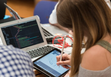 Jugendliche arbeitet mit Laptop und Zeichen-Tablet.