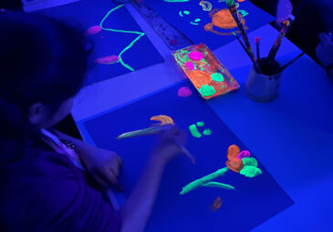 Zeichnen mit leuchtenden Farben in Raum mit Schwarzlicht.